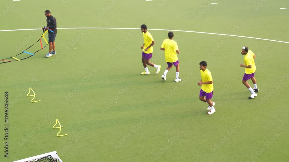 Group of male hockey players training for a game, working out on a field hockey pitch and doing strength exercises Group of male hockey players training for a game, working out on a field hockey pitch and doing strength exercises