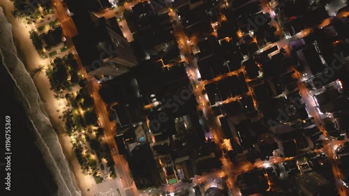 City lights illuminate the shoreline at night, showcasing vibrant urban nightlife by the beach