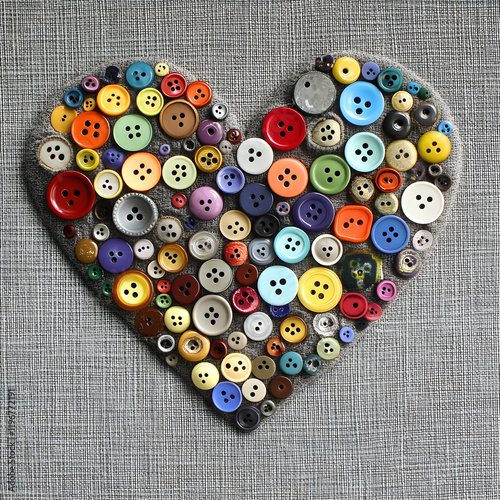 Heart made of colorful buttons arranged on a fabric surface photo