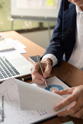 Elderly businessman analyzing data and taking notes in a modern office setting photo