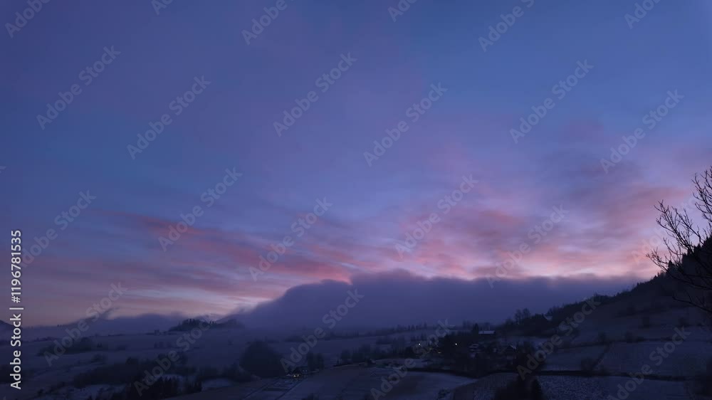 Captivating hyperlapse of vibrant colors of sunset blending with fog rolling over a serene, snowy winter valley and distant hills. Captivating hyperlapse of vibrant colors of sunset blending with fog rolling over a serene, snowy winter valley and distant hills.