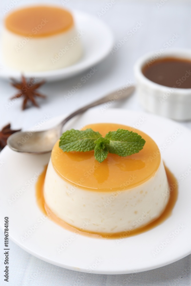 Tasty pudding with caramel sauce served on white tiled table, closeup Tasty pudding with caramel sauce served on white tiled table, closeup