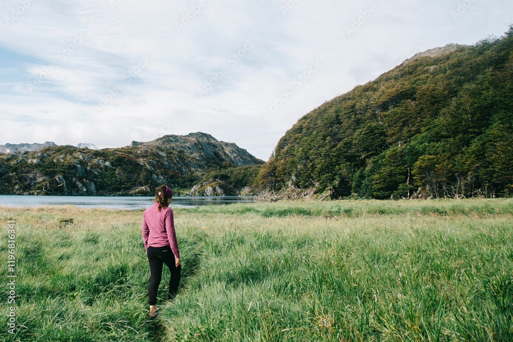 Woman walking towards a lake and mountains. Woman walking towards a lake and mountains.