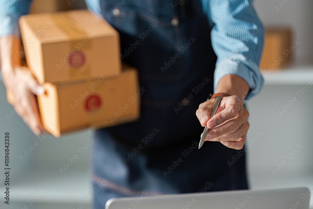 Elderly man holding packages and writing in a modern workspace Elderly man holding packages and writing in a modern workspace