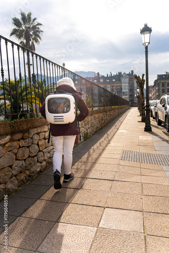 Tourist walking down the street with his cat on his back in a travel backpack photo