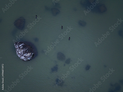 Aerial top down view of the Baltic Sea near Paljassaare Peninsula, Tallinn. Minimalistic composition with scattered rocks beneath tranquil waters creates a captivating, abstract marine landscape.  photo