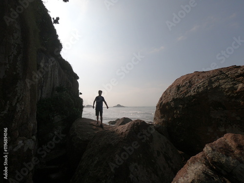 silhueta de homem caminhando entre rochas na beira do mar em itanhaém, são paulo  photo