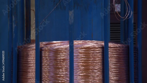 A close-up view of a large copper wire coil, showcasing the intricate winding in an industrial environment.