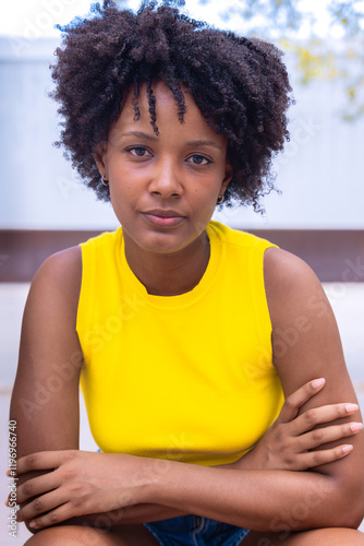 Portrait of black woman with a smiling, thoughtful expression. Focus on her facial features and natural beauty, captured outdoors with soft lighting and an urban background. photo