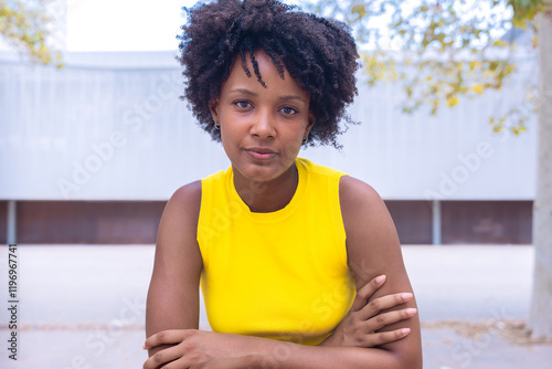 Portrait of black woman with a smiling, thoughtful expression. Focus on her facial features and natural beauty, captured outdoors with soft lighting and an urban background. photo