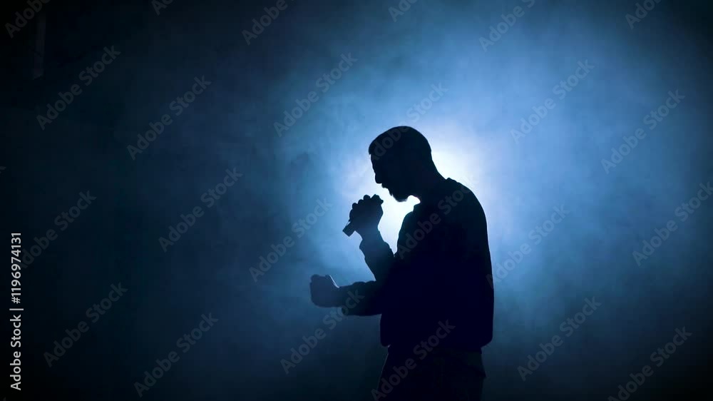 Silhouette of a man singing with a microphone at a concert. Singer artist performing. High quality 4k footage