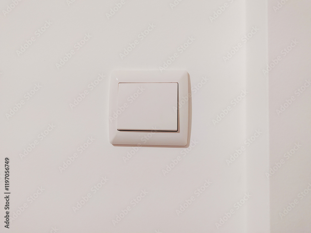Clean, minimalist image of a single white light switch on a white wall. Perfect for interior design, home improvement, or minimalist lifestyle projects.
