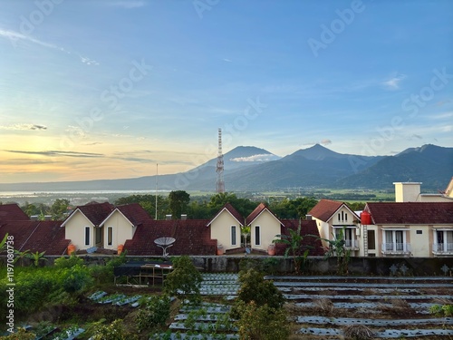 A Dense Residential Area Bathed in the Golden Glow of a Morning Sunrise. A Beautiful Scene of Warm Light Illuminating the Heart of a Bustling Neighborhood with mountain view  photo