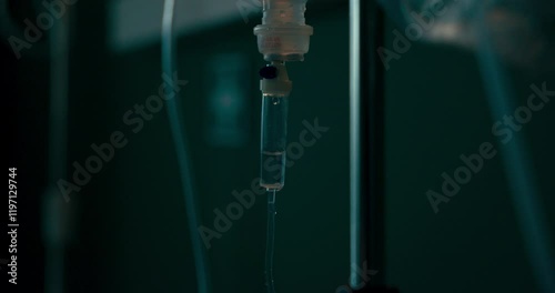IV drip in the foreground with a hospital room in the background.