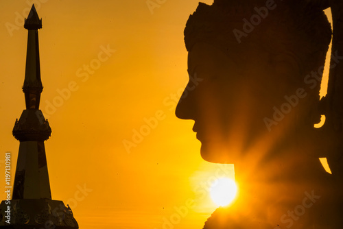 Sunset Silhouette of a Majestic Thai Temple and Statue with Golden Sky at Phetchabun, Thailand. photo