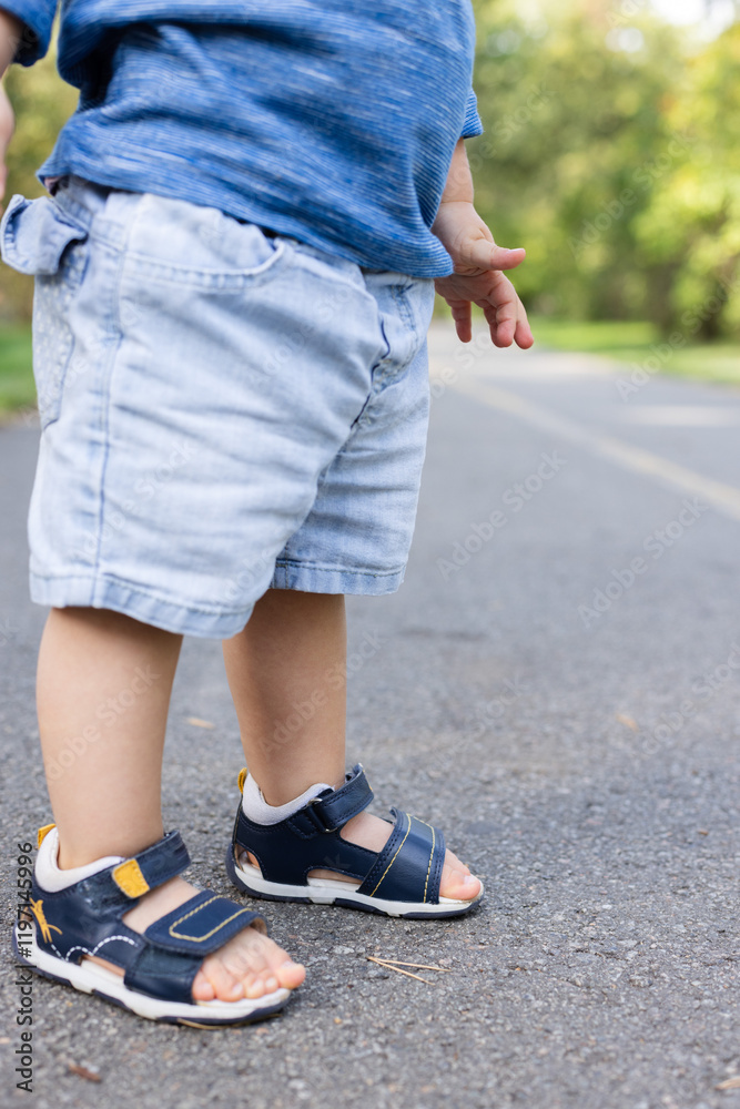Little child walks in too small sandals. Little child walks in too small sandals.