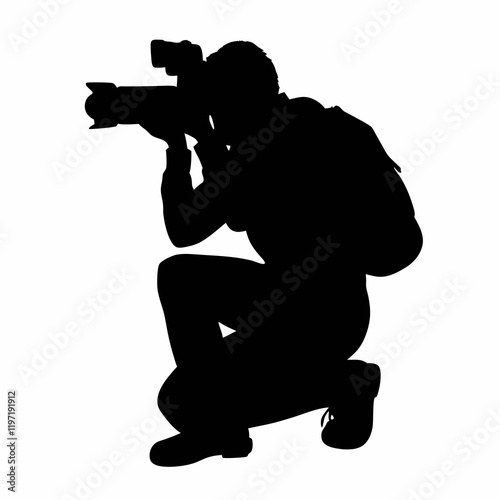 A man is crouching down and taking a picture with a camera. He is wearing a backpack