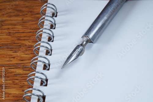 A fountain pen with a pen and a notebook on a wooden table