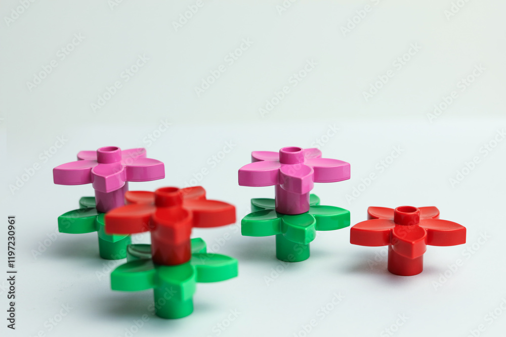 Obraz premium Colorful plastic toy flowers on a white background, shallow depth of field