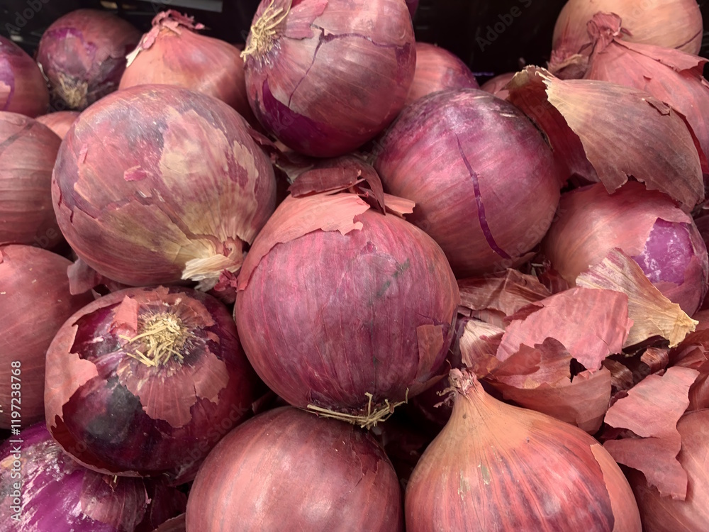 A close-up of several red onions with their papery skins partially peeled off isolated against white background A close-up of several red onions with their papery skins partially peeled off isolated against white background