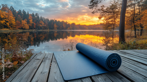Fototapeta Naklejka Na Ścianę i Meble -  Yoga mat on wooden pier at lake in autumn forest at sunset