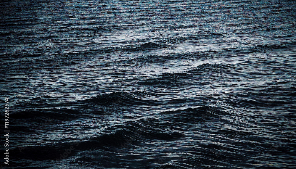 Dark, moody ocean waves ripple across the surface of deep blue waters. Dark, moody ocean waves ripple across the surface of deep blue waters.