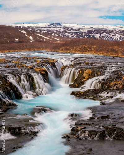 Bruarafoss waterfall with stunning turquoise waters under a bright sky in south Iceland