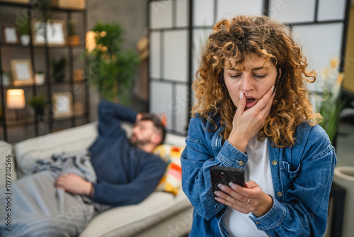 Obraz na plátně shocked wife read message on husband's cellphone while he sleep