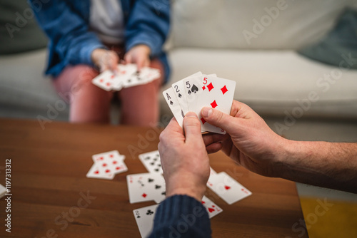 close up of male hands hold and playing cards on wooden table