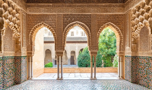 Ornate arches, tiled walls frame courtyard view in historic palace