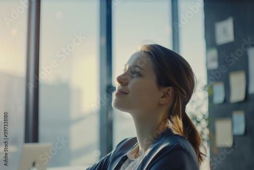 Focused businesswoman in office working on laptop with city view.