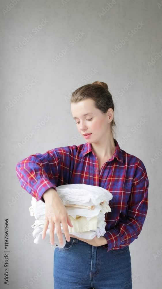 beautiful young woman happily holds stack of colorful things in her hands and smiles at camera. lady folds colorful underwear. concept of clothing recycling. housewife carries laundry to laundry. beautiful young woman happily holds stack of colorful things in her hands and smiles at camera. lady folds colorful underwear. concept of clothing recycling. housewife carries laundry to laundry.