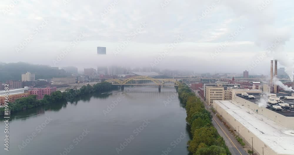 An early morning foggy reverse aerial establishing shot of the Pittsburgh skyline with the Steel Building poking up above the fog. The Allegheny River is in the foreground. An early morning foggy reverse aerial establishing shot of the Pittsburgh skyline with the Steel Building poking up above the fog. The Allegheny River is in the foreground.