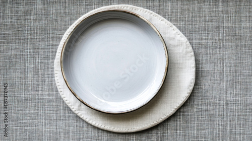 Elegant minimalist plate design featuring a simple white dish arranged on a soft textured linen background, showcasing modern dining aesthetics and simplicity in tableware.