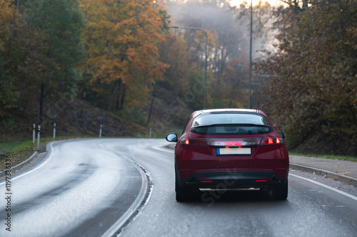Rear view of a red car on a bend in an autumn road