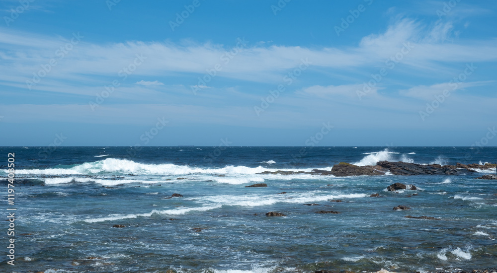 Coastal scene, ocean waves breaking on rocky shore, blue sky with clouds. Coastal scene, ocean waves breaking on rocky shore, blue sky with clouds.