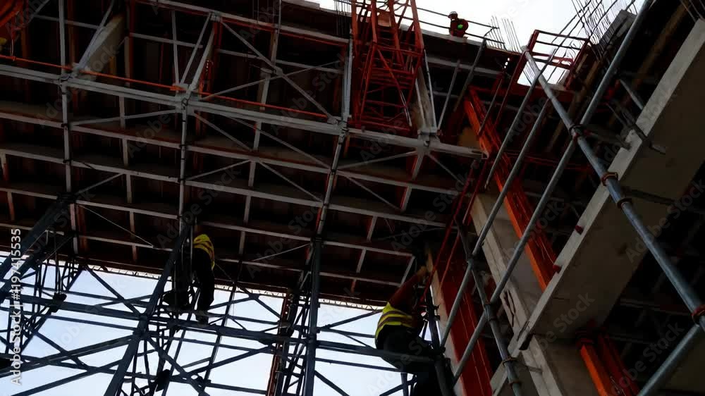 Tower cranes and workers at high concrete residential building under construction Tower cranes and workers at high concrete residential building under construction