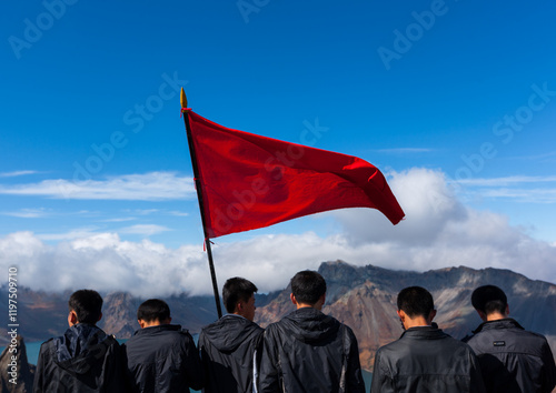 Group of students with red flag in front of lake at mount Paektu, Ryanggang Province, Mount Paektu, North Korea photo