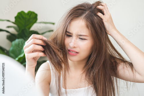 Damaged Hair, frustrated asian young woman, girl hand in holding splitting ends, messy unbrushed dry hair with face shock, long disheveled hair, health care of beauty, dry and frizzy hair concept
