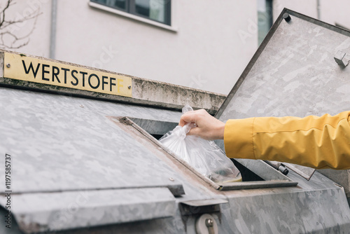 unrecognizable person,  throwing plastic bag into Wertstoff recycling bin promoting environmental sustainability photo