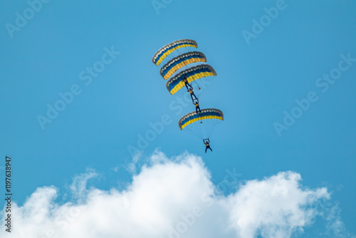 Scenic parachutists formation airshow with yellow-blue ukrainian parachutes above clouds photo