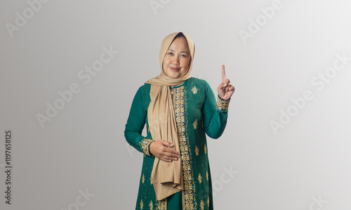 Cheerful Woman in Traditional Green Dress Pointing Upward with One Finger
