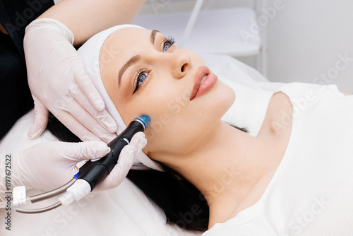 In a cosmetology clinic, a professional female cosmetologist performs a hydrafacial treatment on an attractive woman. Concept of beauty, skincare, and rejuvenation with advanced facial procedures. photo