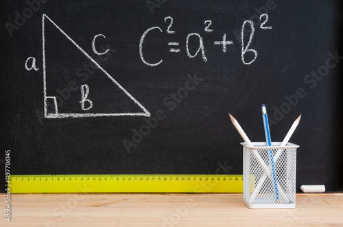 Pencil holder and ruler  in front of black chalkboard with Pythagorean theorem