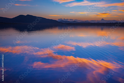 Landscape of mountains and lake at sunset and clouds reflected in the water.