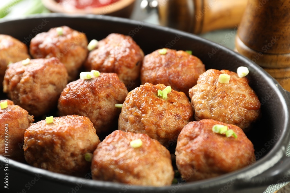 Tasty meatballs with green onion in baking dish on table, closeup Tasty meatballs with green onion in baking dish on table, closeup