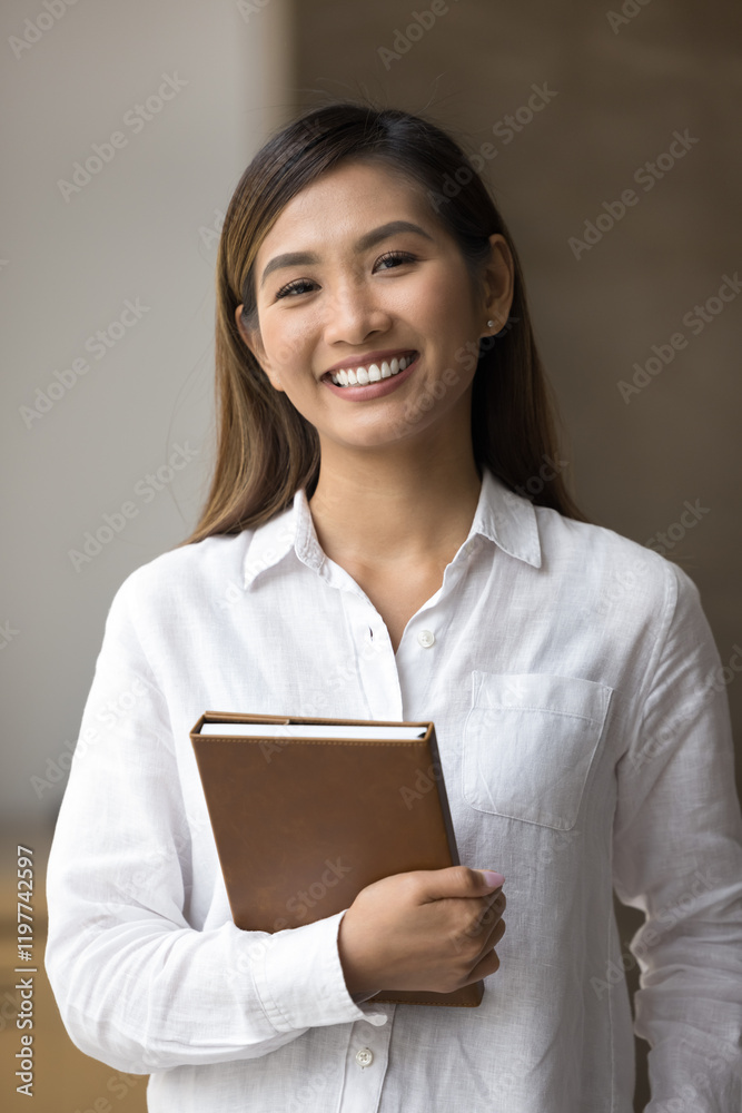 Attractive young Asian businesswoman look at camera with smiling expression, pose alone in corporate office, vertical shot. Female CEO, executive manager or secretary front view, professional portrait Attractive young Asian businesswoman look at camera with smiling expression, pose alone in corporate office, vertical shot. Female CEO, executive manager or secretary front view, professional portrait