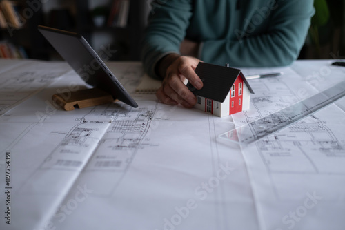 Architect man holding pencil working with laptop and blueprints for architectural plan, engineer sketching a construction project concept.