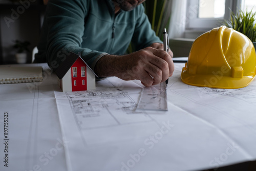 Architect man holding pencil working with laptop and blueprints for architectural plan, engineer sketching a construction project concept.