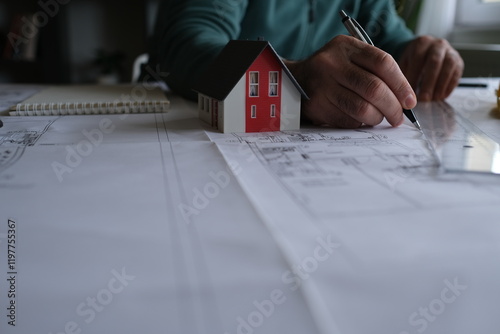 Architect man holding pencil working with laptop and blueprints for architectural plan, engineer sketching a construction project concept.